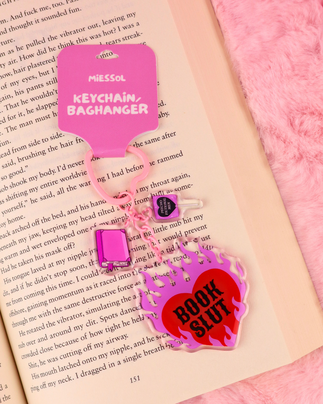 Pink and red Book Slut keychain with heart-shaped hardware and three bookish charms, a funny book lover accessory for bags, keys and book sleeves.