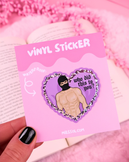 Heart-shaped sticker with a person wearing a black mask and text 'who did this to you?' held by a hand against a pink background. booktok masked men, fictional men, dark romance