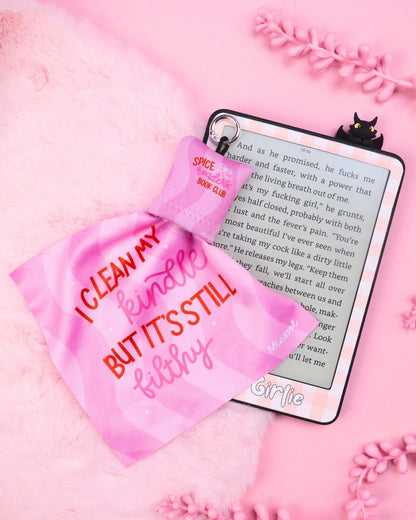 Pink cleaning pouch labeled 'I clean my Kindle but it's still filthy' on a pink background with a Kindle device.